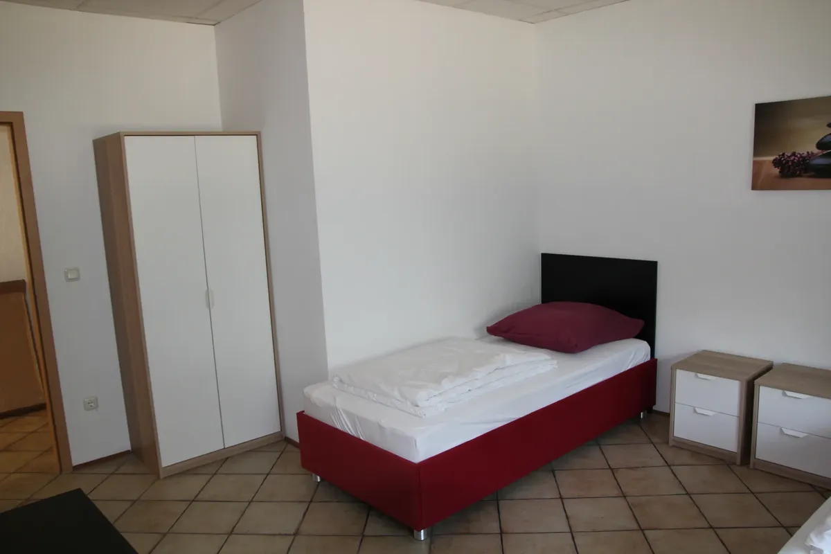 Einzelzimmer mit Bett, Schrank und Nachttisch